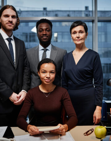 Portrait of successful team of business people posing professionally in corporate office and looking at camera