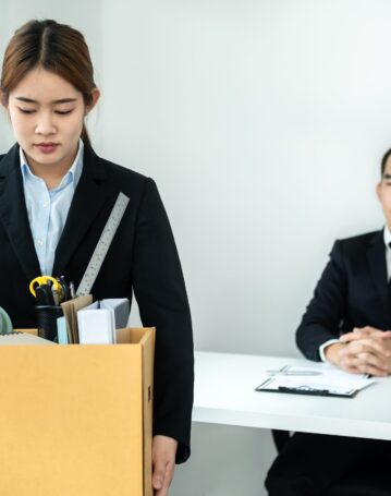 Business woman employee in suit is stressed and carrying persona Business woman employee in suit is stressed and carrying personal belongings in brown cardboard box to walking out workplace after sending resignation letter to executive in office