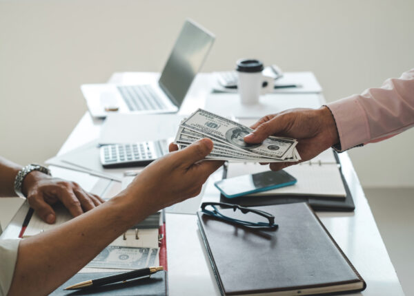 Businessman giving money to his partner. Bribe and corruption concept.